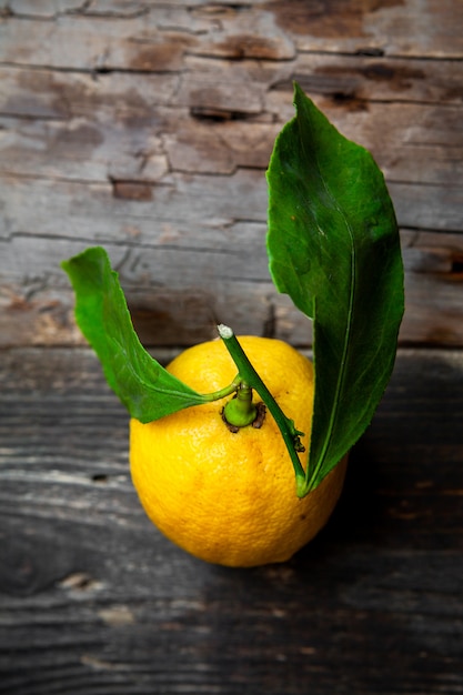 Top view lemon with leaves on dark wooden background. vertical