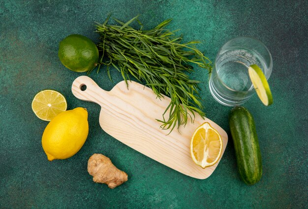緑の表面にタラゴングリーンと生姜の木製キッチンボード上のレモンのトップビュー