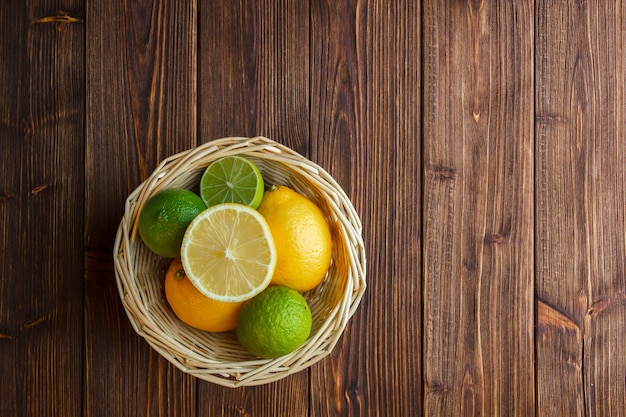 Лимоны вид сверху в корзине на деревянных фоне.