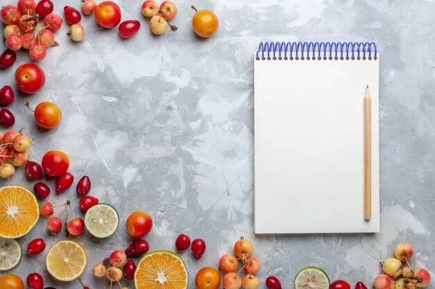 Top view lemons and cherries fresh fruits with notepad on the light desk fruit fresh mellow ripe