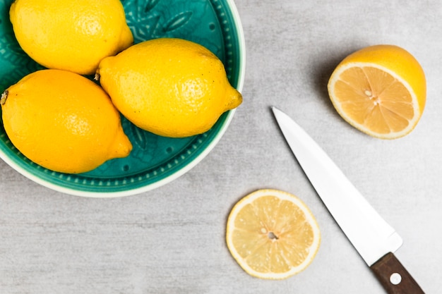 Top view of lemons and knife on wooden table