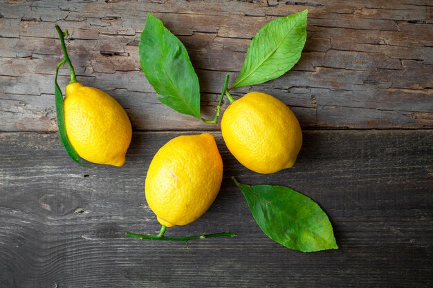 Top view lemons with leaves on dark wooden background. horizontal