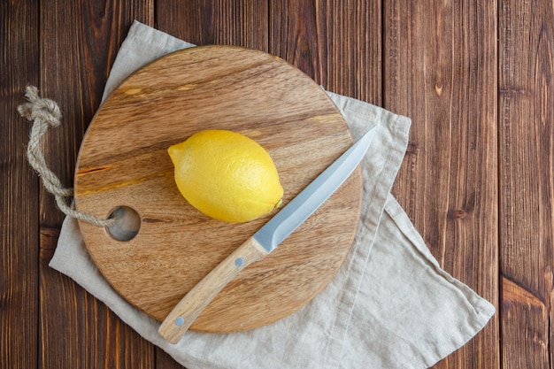 Top view lemons with lemon on cutting board on wooden surface. vertical