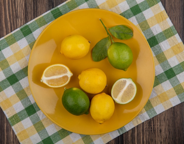 Top view lemons with limes on a yellow plate  on a yellow-green checkered towel