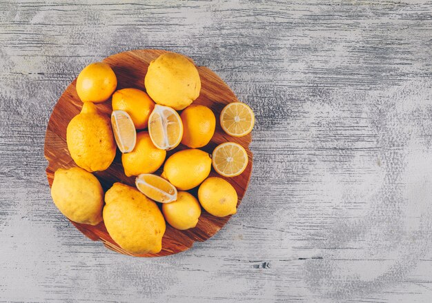 Top view lemons in wooden platform with slices on gray wooden background. horizontal space for text