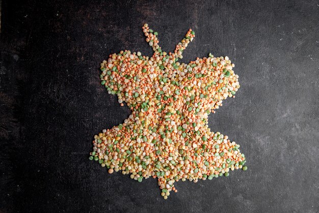 Top view lentils forming butterfly shape on dark textured background. horizontal