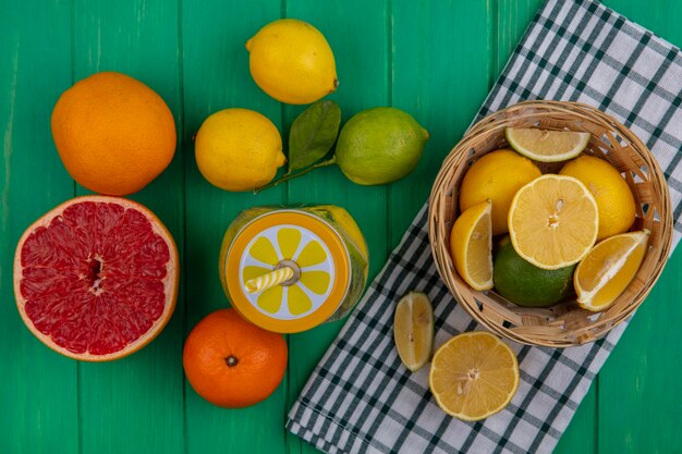 오렌지와 녹색 배경에 반 자몽 체크 무늬 수건에 바구니에 레몬 상위 뷰 라임 조각