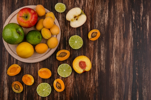 Top view of lime slices with peach, apricots and apple on a wooden surface