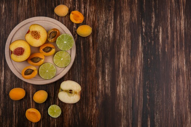 Вид сверху ломтиков лайма с персиковыми абрикосами и яблоком на деревянной поверхности