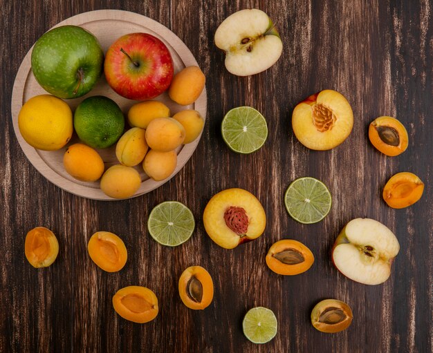 Top view of lime slices with peach apricots and apple on a wooden surface