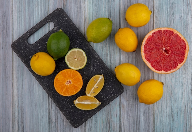 Vista dall'alto uno spicchio di lime con mezza arancia pompelmo e limone sul tagliere su sfondo grigio