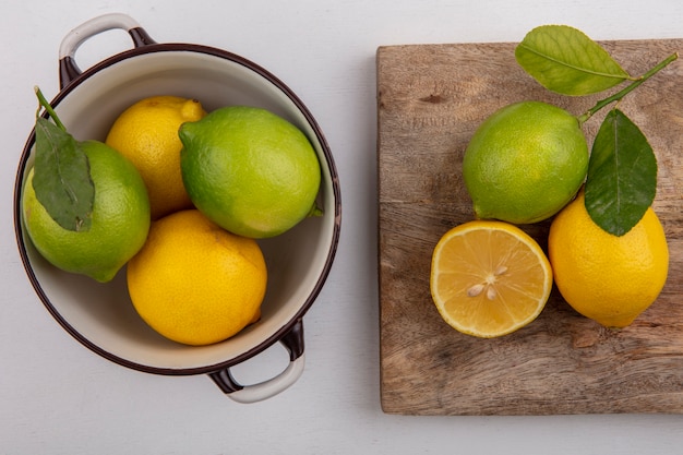 Top view lime with lemon in a saucepan and on a blackboard on a white background