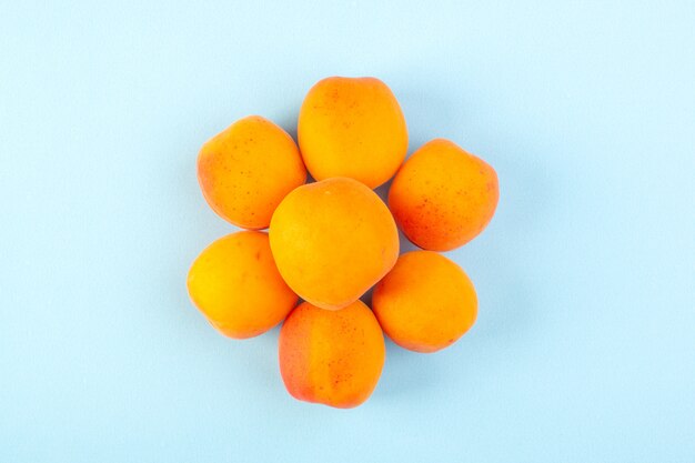 Вид сверху облицованных апельсиновыми персиками, свежими спелыми, изолированными на ледяном синем фоне, фруктовый витаминный сок