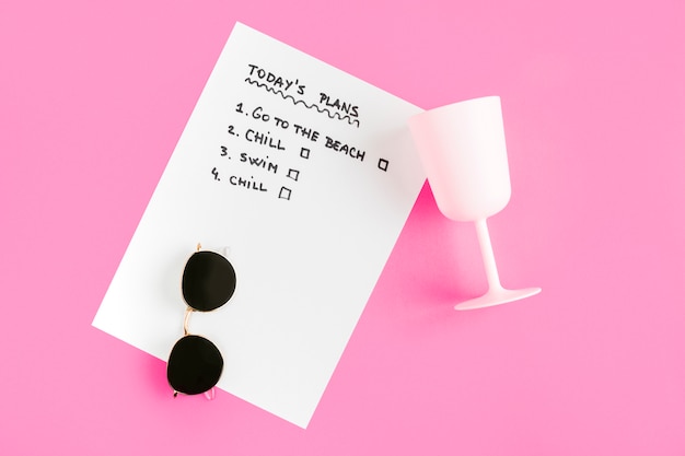 Top view list with cup and sunglasses