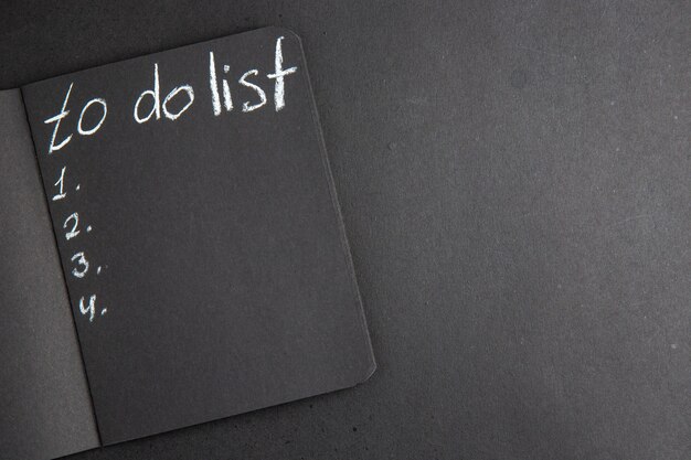 Top view to do list written on black notebook on black table free space