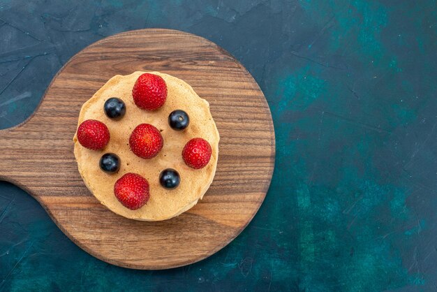 Top view little cake baked round formed with fresh strawberries on dark-blue surface