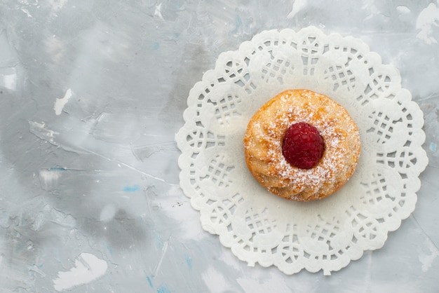 Foto gratuita vista dall'alto piccola torta di zucchero a velo con lampone sulla superficie chiara