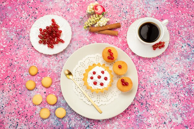 Top view little cake with cream cookies fresh cranberries along with cup of coffee and cinnamon on the colored surface cake sweet 