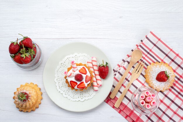 Top view of little cake with cream and sliced strawberries cakes candies on white desk, fruit cake berry sweet sugar