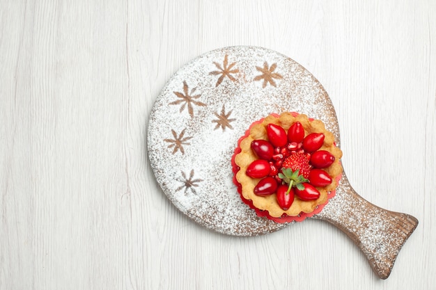 Vista dall'alto piccola torta con frutta fresca sulla scrivania bianca