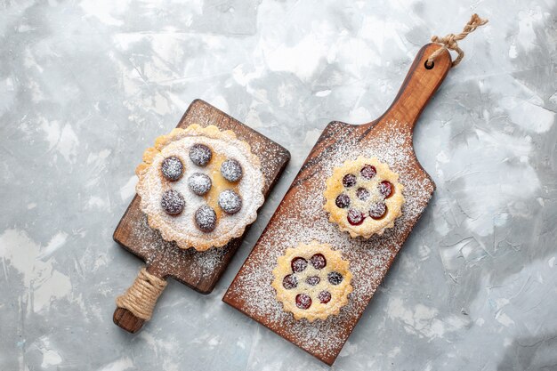 Top view little cakes sugar powdered with fruits on the light desk fruit biscuit cake sweet sugar