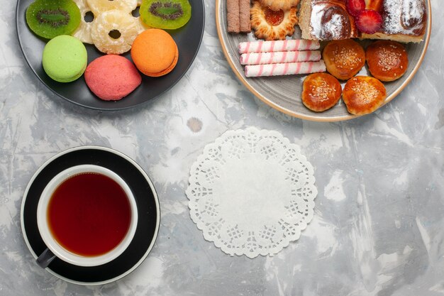 上面図白いバックグラウンドクッキービスケット甘い砂糖パイティーにお茶とデザートのクッキーカップと小さなケーキ
