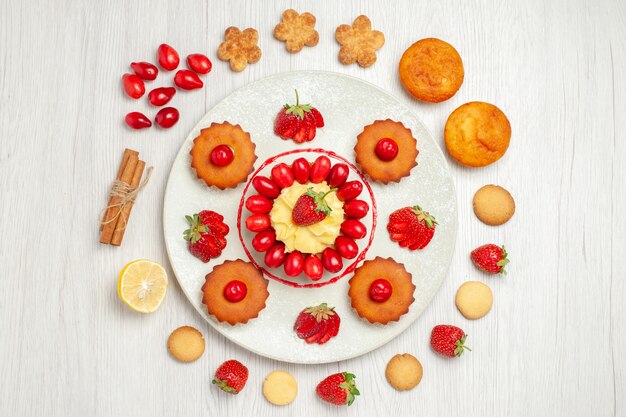 흰색 책상에 접시 안에 과일과 함께 상위 뷰 작은 케이크
