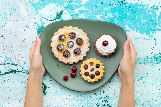 Top view little cakes with sugar powder fruits cream inside plate on blue table cake cream fruit sweet tea