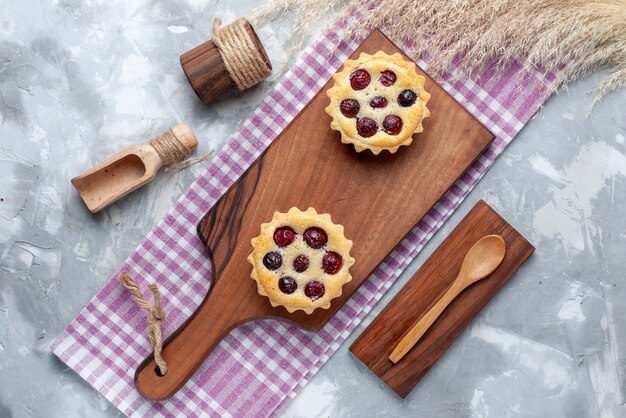 Top view little cakes with sugar powder fruits cream on light table cake cream sweet tea