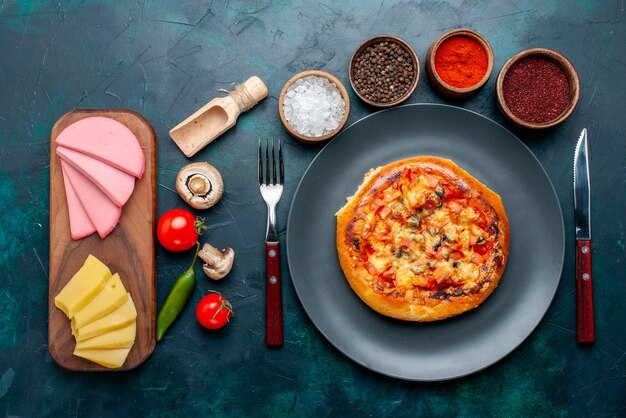 Top view of little cheese pizza round formed with seasonings cheese on dark blue surface