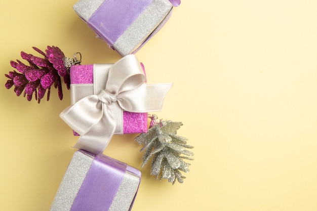 Top view of little christmas presents on light-yellow surface