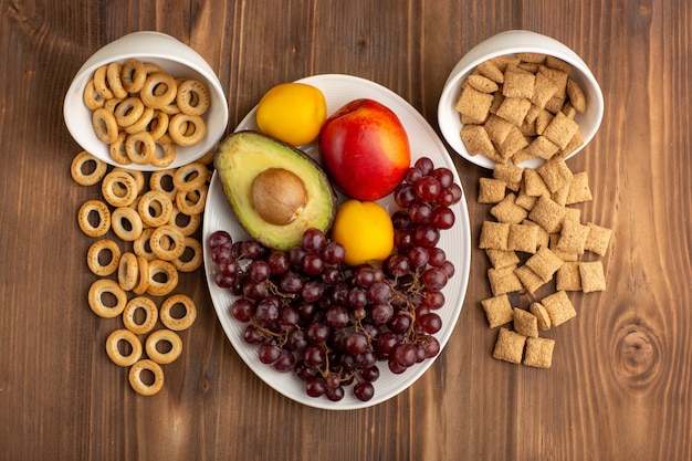 Top view little cookies and crackers with fruits on brown wooden desk