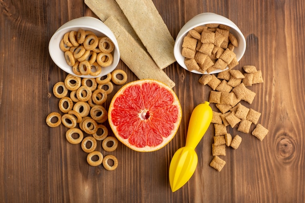 Foto gratuita vista dall'alto piccoli biscotti e cracker con pompelmo sullo scrittorio di legno marrone