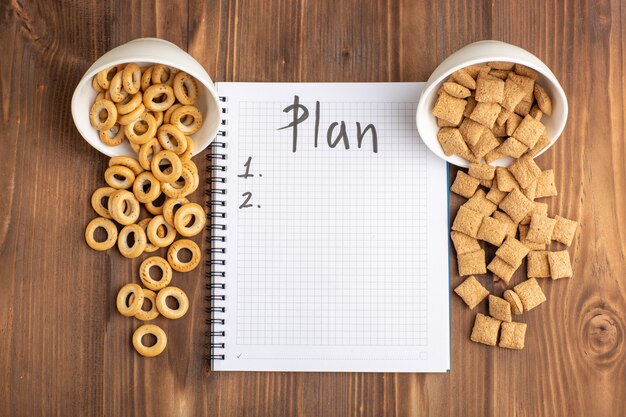 Top view little cookies and crackers with notepad on brown wooden desk