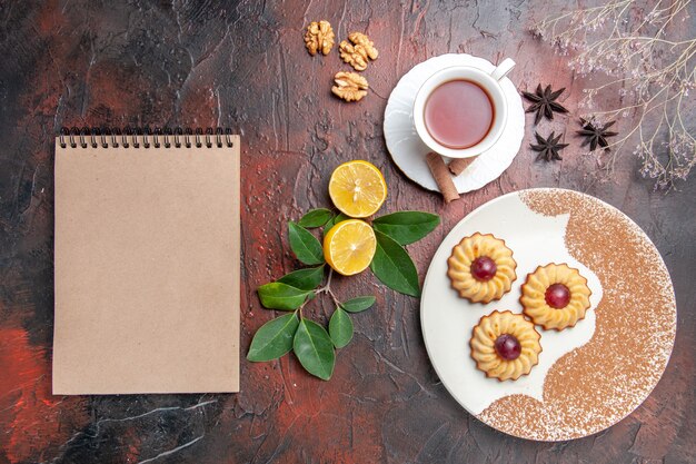 Top view little cookies with cup of tea on dark table sugar biscuit cake