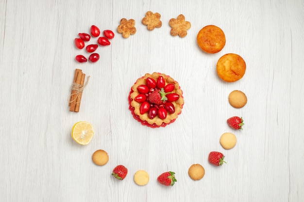 Foto gratuita vista dall'alto piccoli biscotti con frutta e torta sulla scrivania bianca