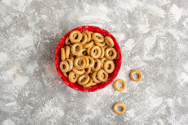 Top view little crackers inside red plate on white surface