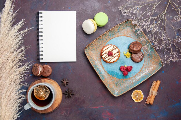 Top view little creamy cake with chocolate cookies and cup of tea on the dark surface biscuit sweet pie sugar cookie cake