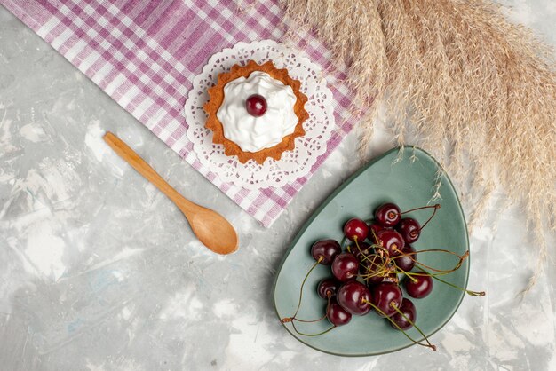 トップビューライトテーブルケーキティーフルーツスイートクリームに新鮮なチェリーと小さなクリーミーなケーキ