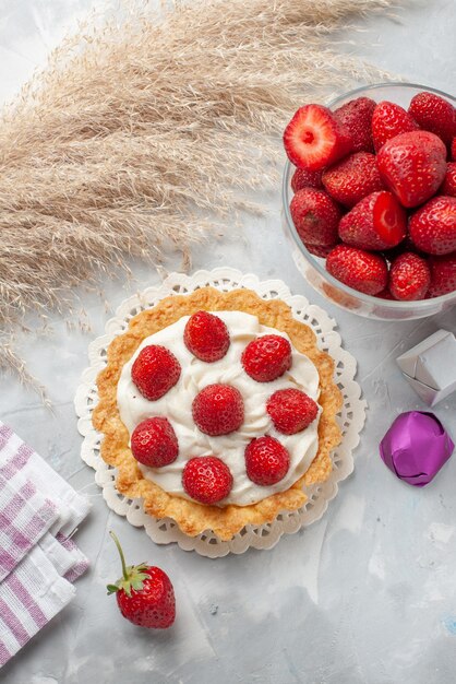 Вид сверху маленький кремовый торт со свежей красной клубникой и шоколадным конфетами торт на белом столе торт фруктовый ягодный бисквитный крем
