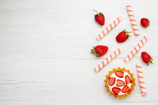 Top view little creamy cake with fresh strawberries and candies on the light background cake sweet photo fruit berry bake