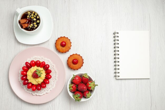 흰색 책상에 과일과 차 한잔과 함께 상위 뷰 작은 크림 케이크