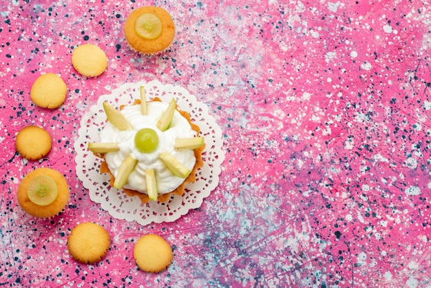 Top view little creamy cake with sliced fruits cookies on the colored desk cake sweet sugar color photo