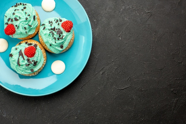 Top view little creamy cakes delicious sweets for tea inside plate on dark floor cream cake biscuit dessert tea color