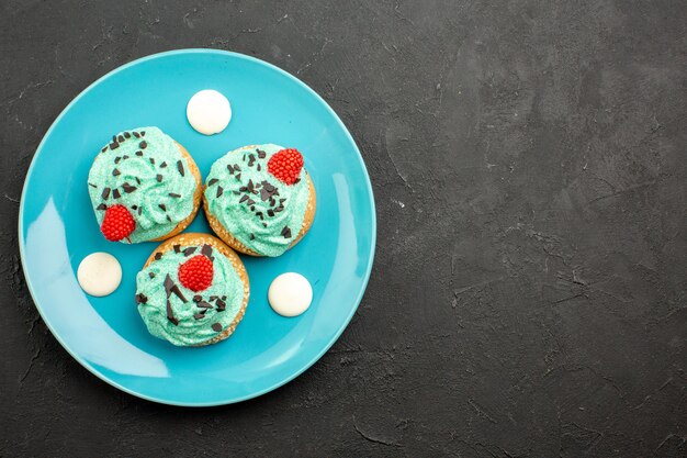 Top view little creamy cakes delicious sweets for tea inside plate on a dark surface cream cake biscuit dessert tea color