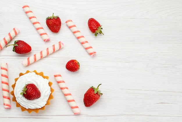 Вид сверху маленькие кремовые пирожные со свежей клубникой и конфетами на светлом столе торт сладкое фото фруктово-ягодная выпечка