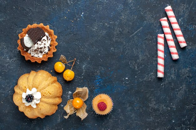어두운 배경 비스킷 케이크 달콤한 과일에 쿠키와 핑크 스틱 사탕과 함께 상위 뷰 작은 맛있는 케이크