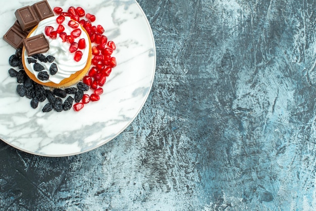 Foto gratuita vista dall'alto piccola deliziosa torta con cioccolato e uvetta su sfondo chiaro-scuro