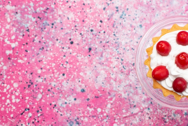 Vista dall'alto piccola deliziosa torta con crema e frutti rossi sulla superficie brillante zucchero dolce