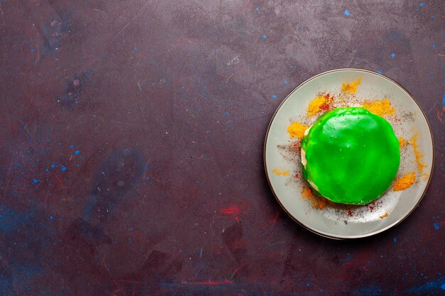 Top view little delicious cake with green cream inside plate on the dark desk